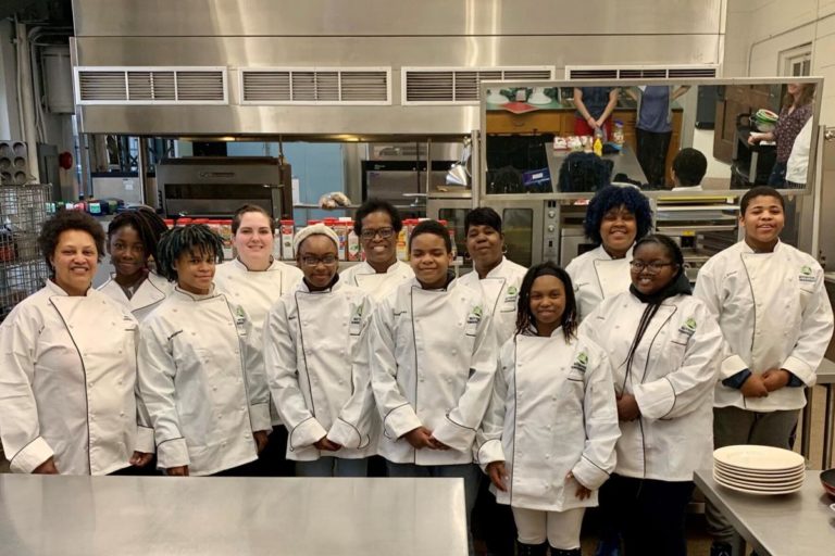 High school students serving as nutrition ambassadors wear chef coats.