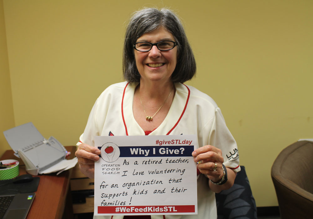 Volunteer posing with a "Why I Give" poster