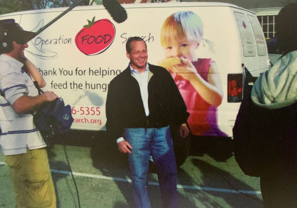 Volunteer being interviewed in front of Operation Food Search Van