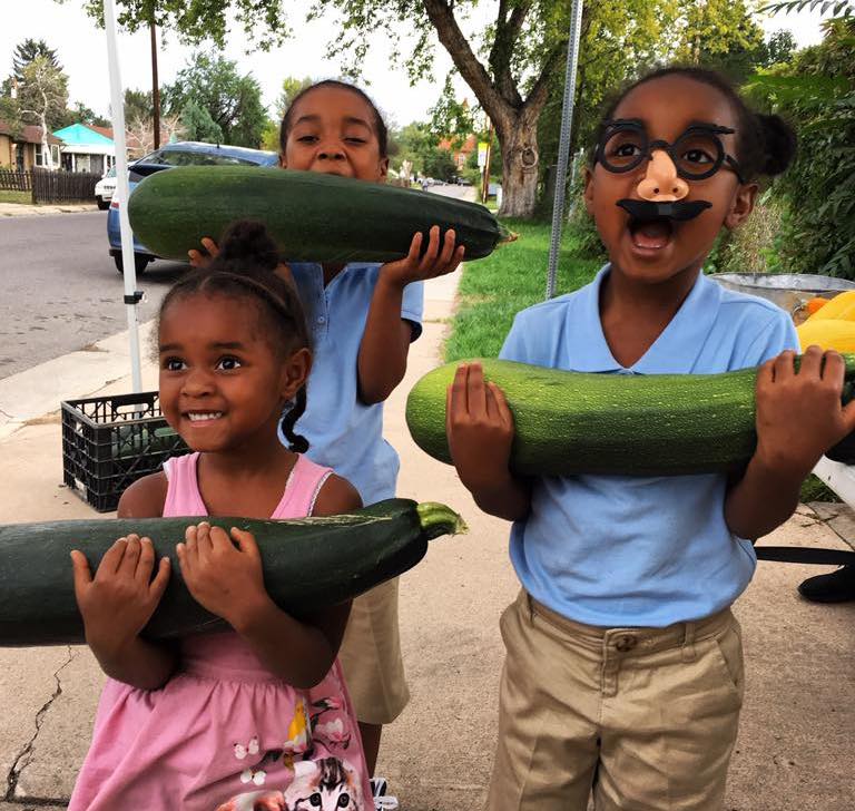 Girls holding large zucchini