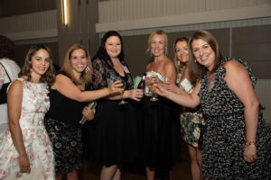 A group of women raise their glasses in a toast.