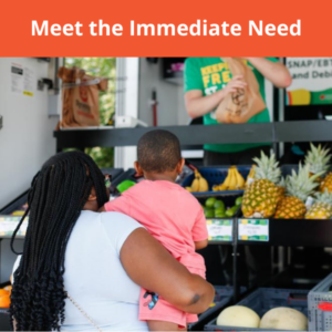 Woman holding baby as she shops for fresh food